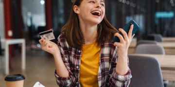 A happy woman using credit card cashback rewards.